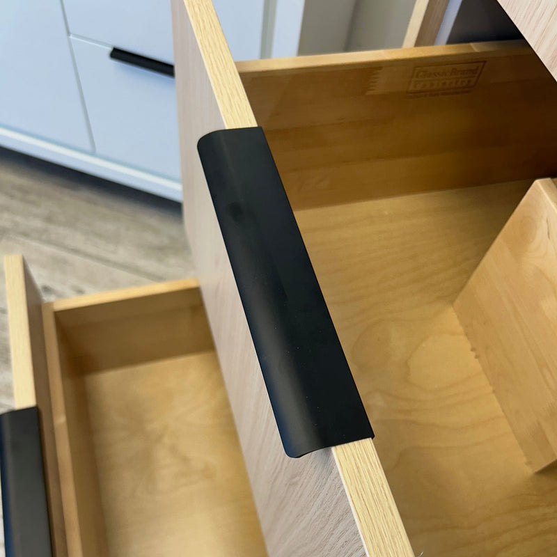 Wooden drawer with a black handle on a wooden surface.