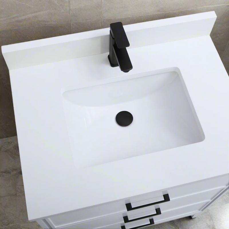 White bathroom sink with black faucet and drain cover on a tiled wall background