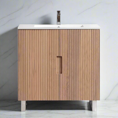 Fluted bathroom vanity with wooden cabinet and white countertop against a marble wall.